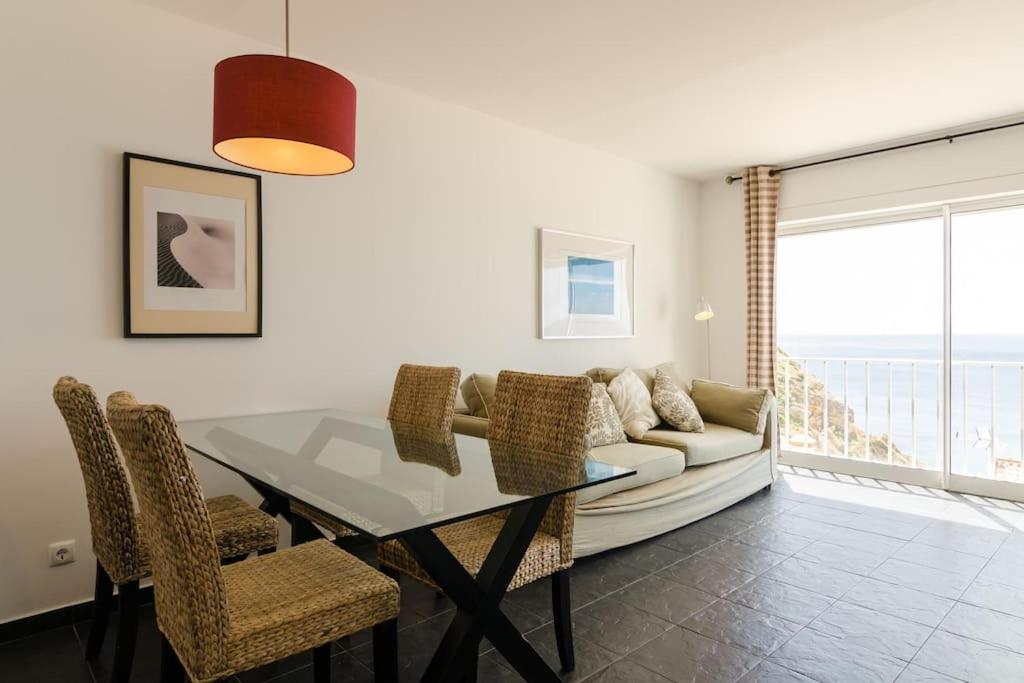 a dining room with a table and chairs and a couch at apartment with amazing sea view in Burgau