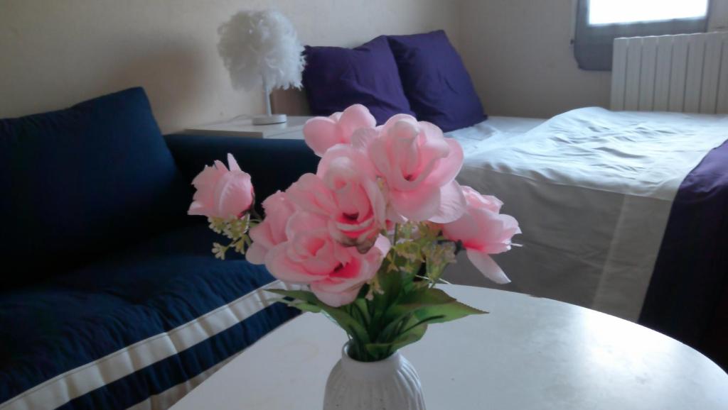 a vase with pink flowers on a table in a room at Petite maison indépendante avec terrasse privée in Montmorillon