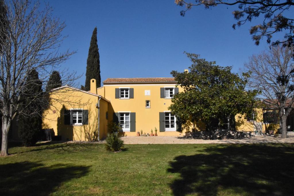 a large yellow house with a tree in front of it at Lumineux deux pièces en rez de jardin in Hyères