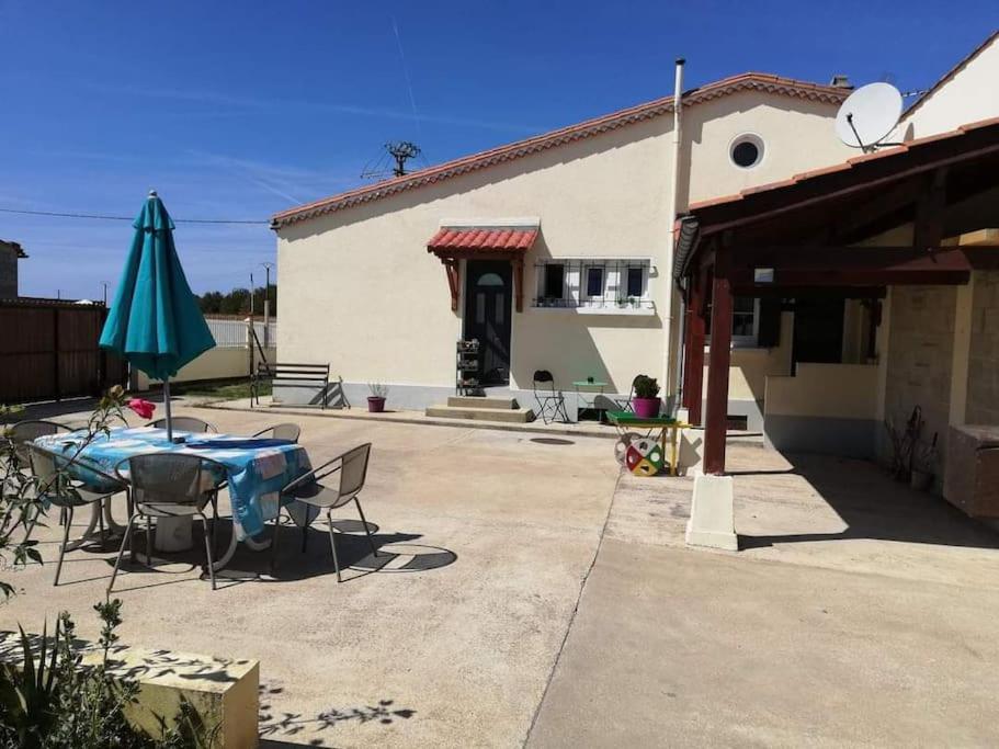 un patio con una mesa y una sombrilla y un edificio en gite des huskys en Tonnay-Charente