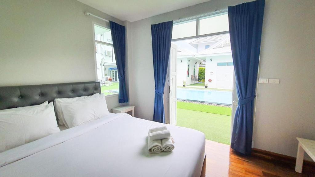 a bedroom with a bed and a large window at Bianco House Resort in Cha Am