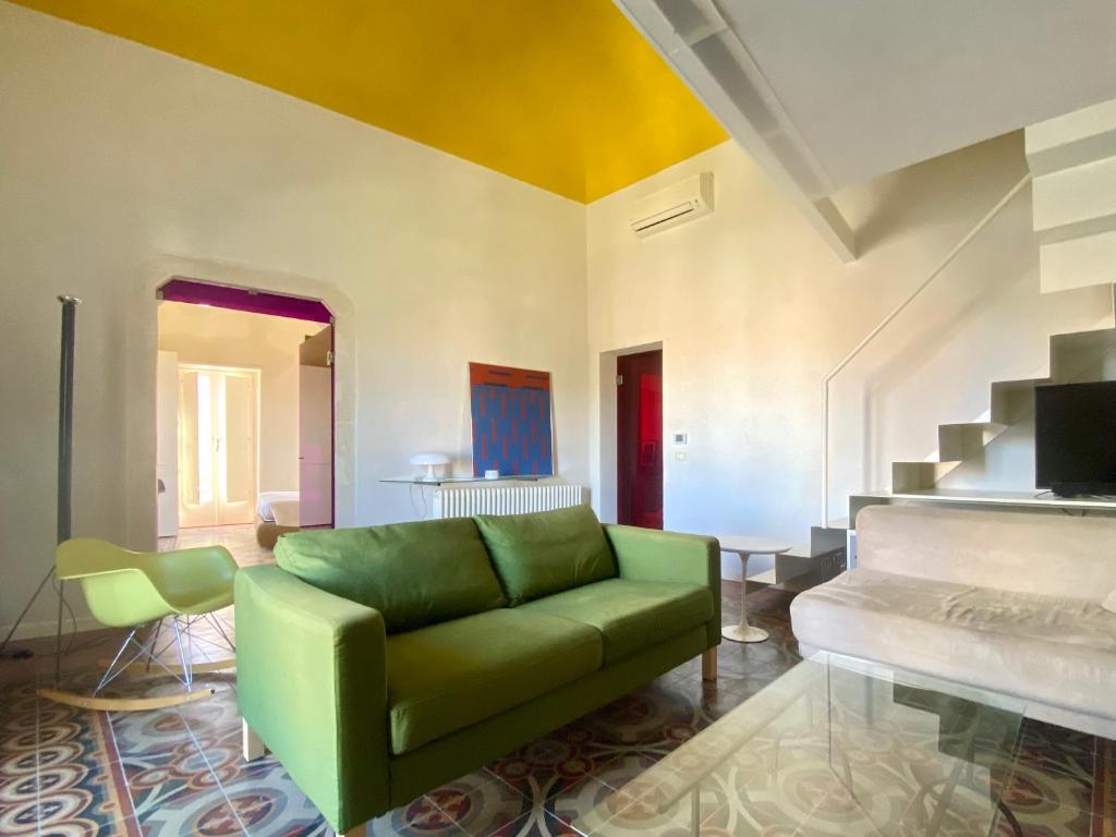 a living room with a green couch and a staircase at KLEOMENE tempio di Apollo in Siracusa