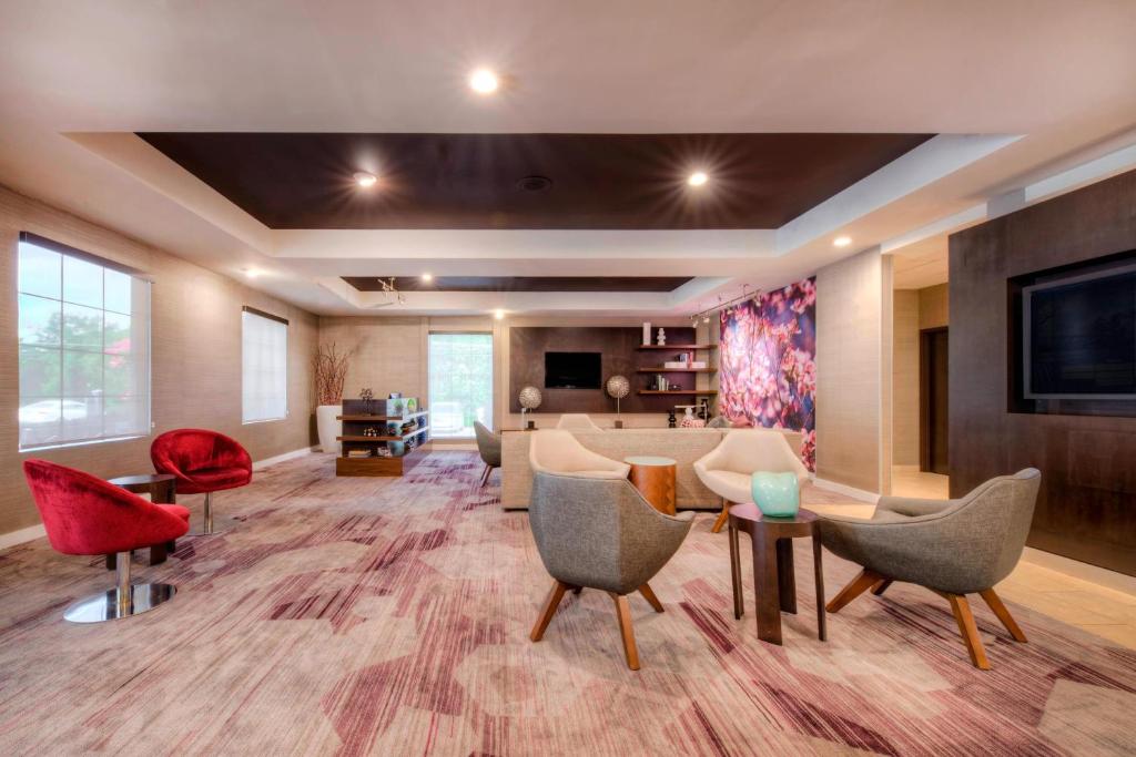 a living room with chairs and a couch and a tv at Courtyard Raleigh Crabtree Valley in Raleigh