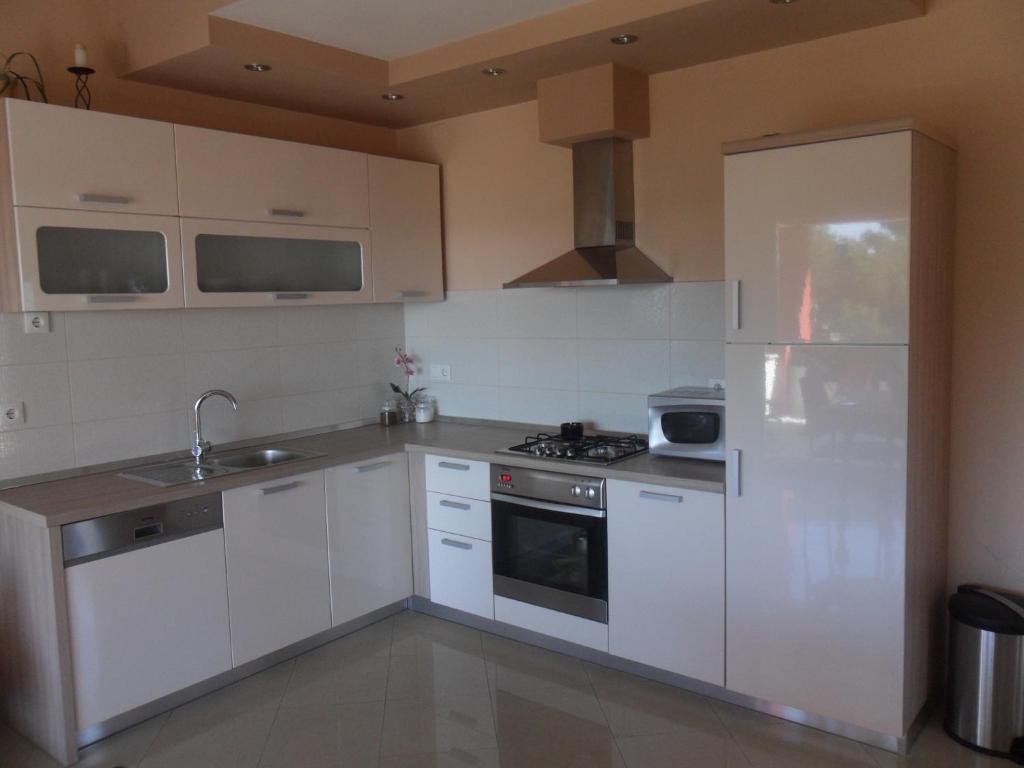 a kitchen with white cabinets and a sink and a refrigerator at Apartman Toni in Bibinje