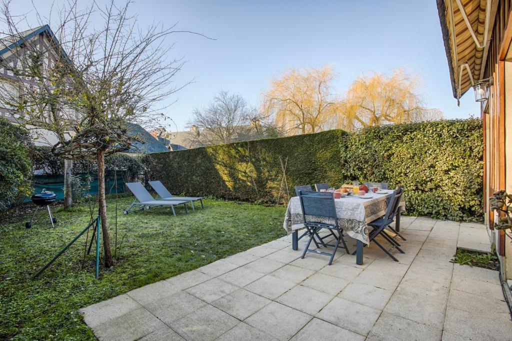 a patio with a table and chairs in a yard at Maison vélo piscine tennis in Deauville