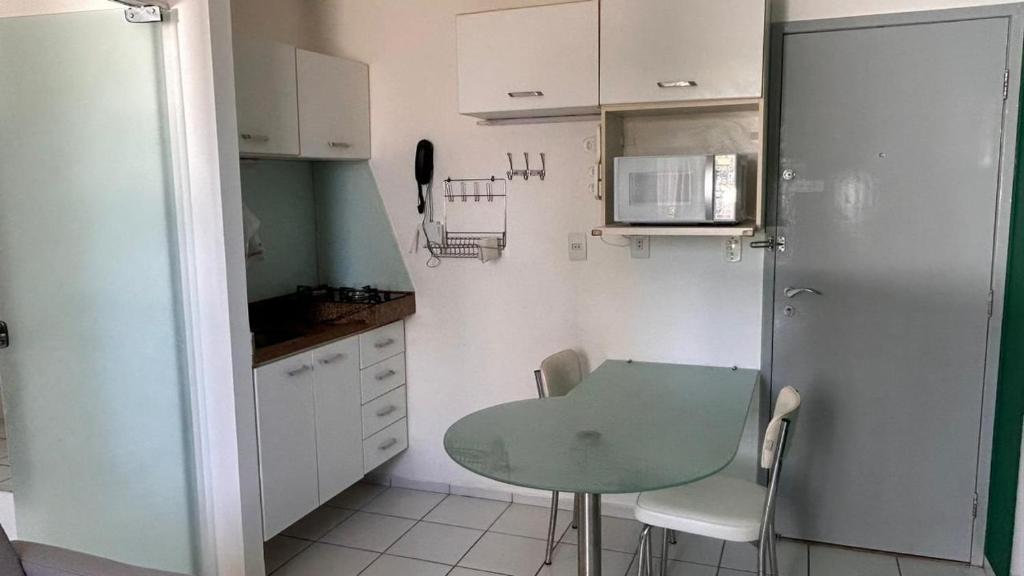 una pequeña cocina con una mesa verde y armarios blancos en Lindo Apartamento com piscina à 100m do MAR, en Recife
