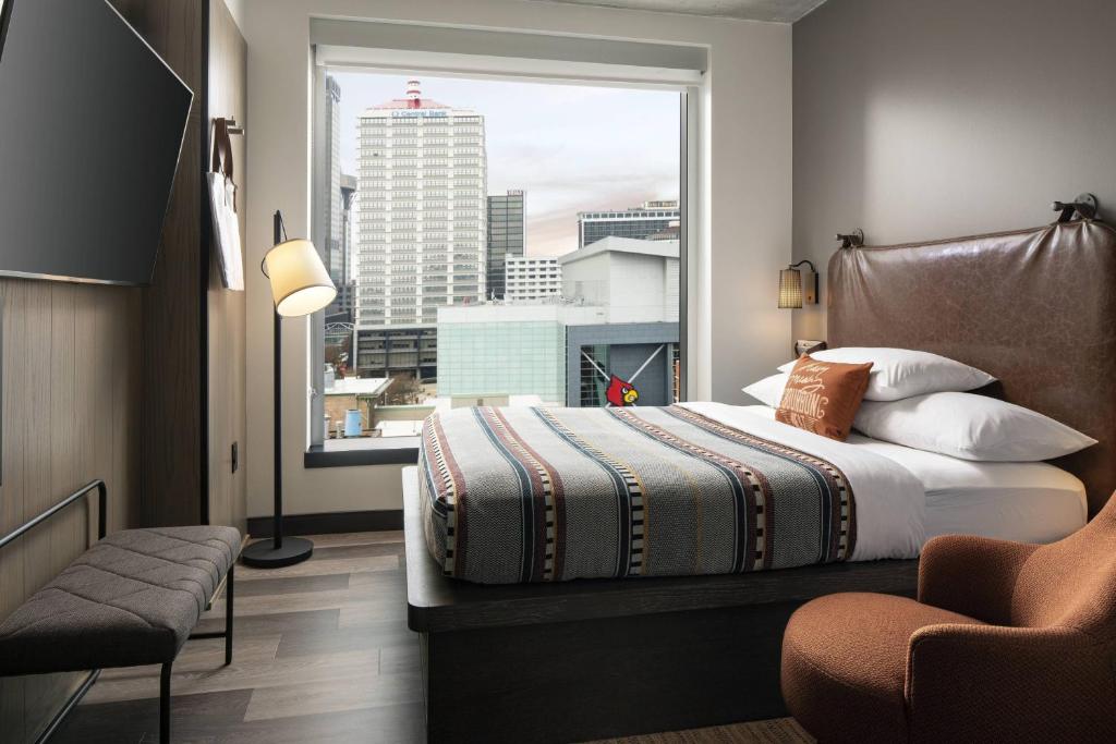 a bedroom with a bed and a large window at Moxy Louisville Downtown in Louisville