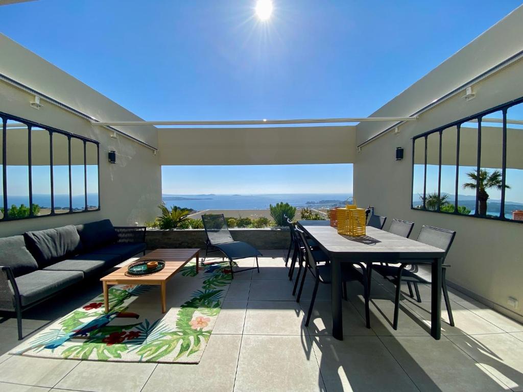 een patio met een tafel en stoelen en een bank bij Superbe T2 44m2 - Grande terrasse Vue mer panoramique exceptionnelle Piscine - Parking in Bandol