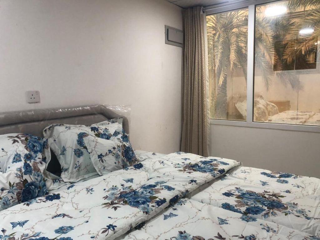 a bed with blue and white sheets and a window at Haret Nizwa hostel in Nizwa