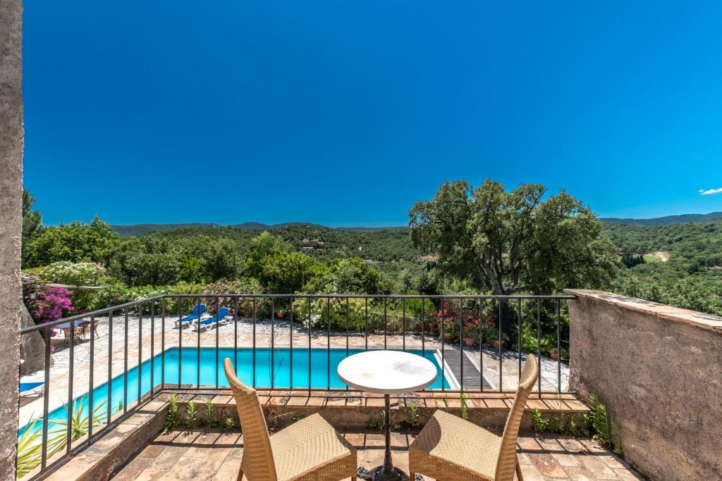 a balcony with a table and chairs and a pool at Hôtel La Boulangerie in Grimaud