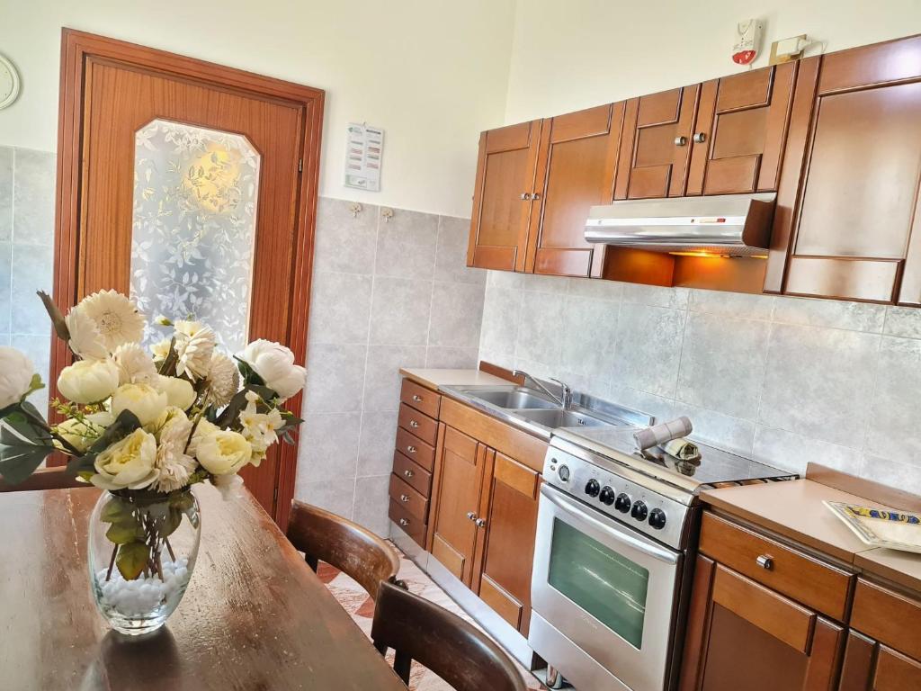 Italian Experience-Casa Vittoria في كافا مانارا: مطبخ مع طاولة عليها إناء من الزهور