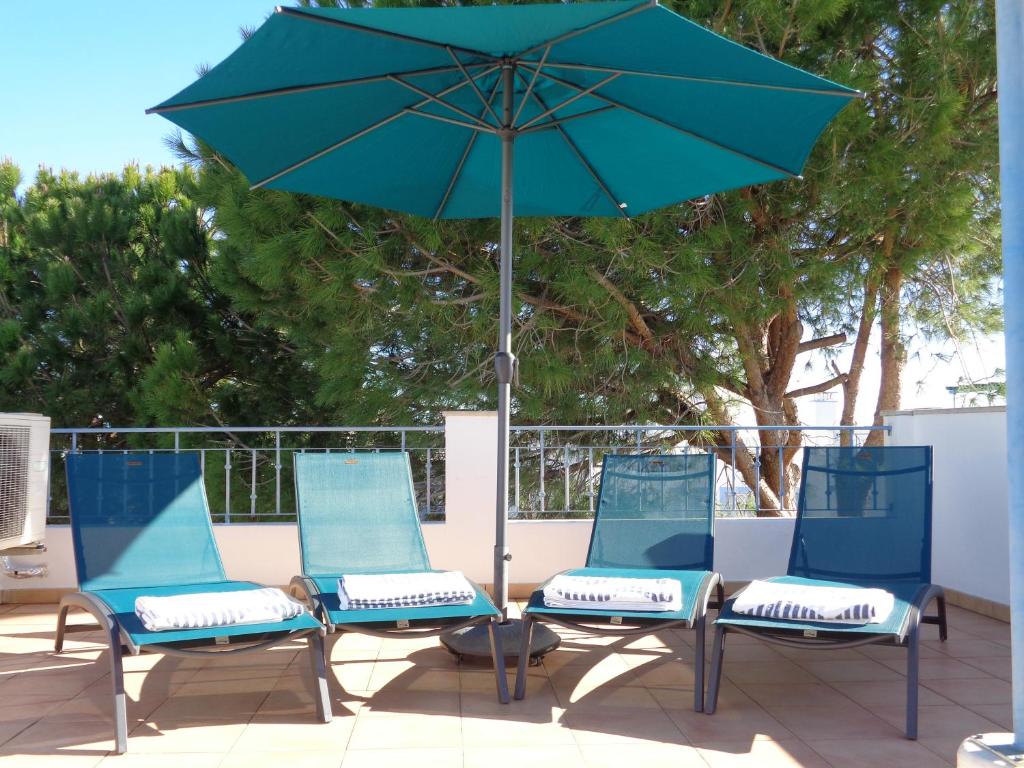 três cadeiras e um guarda-sol num pátio em Farol da Cortesia - Praia Verde em Praia Verde