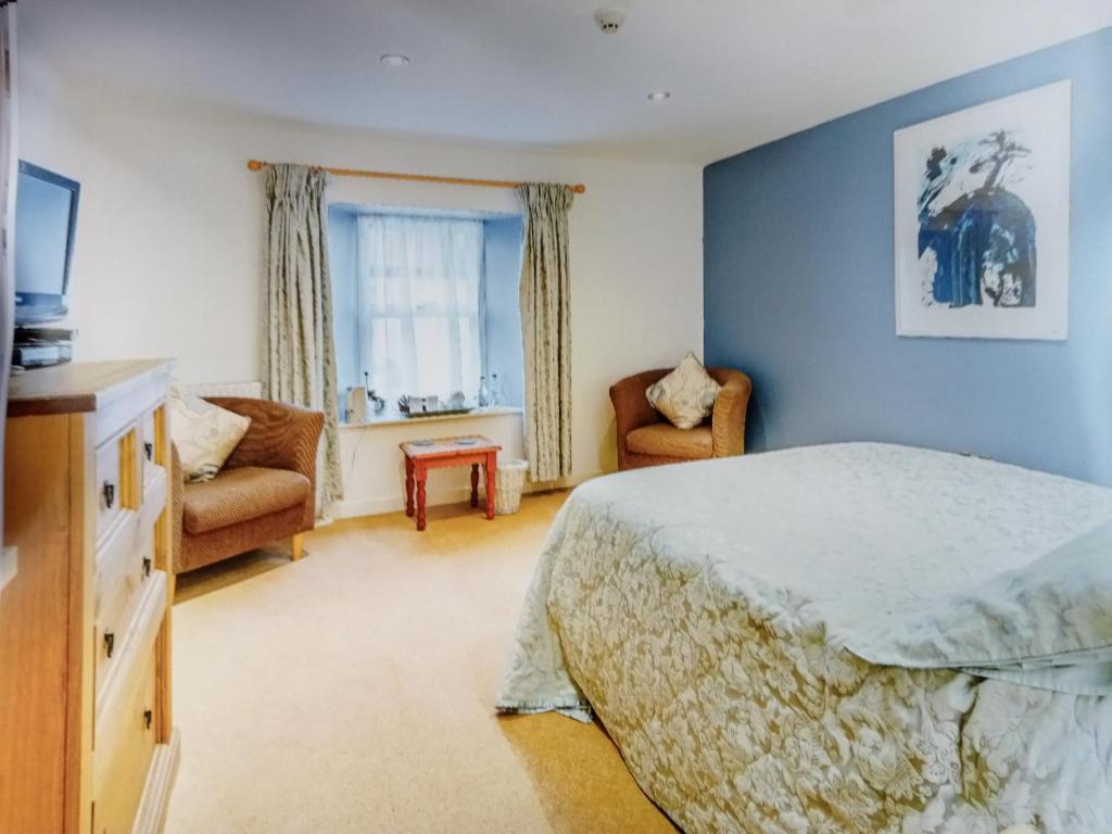 um quarto com paredes azuis e uma cama e cadeiras em The Boat House Bed and Breakfast em Laugharne