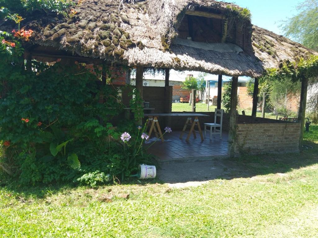 Casa con techo de paja, mesa y silla en La Candela en Gualeguaychú