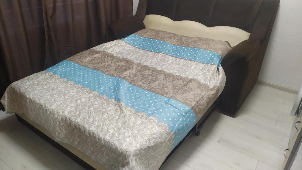 a bed with a blue and gray blanket on it at Квартира студия in Chişinău