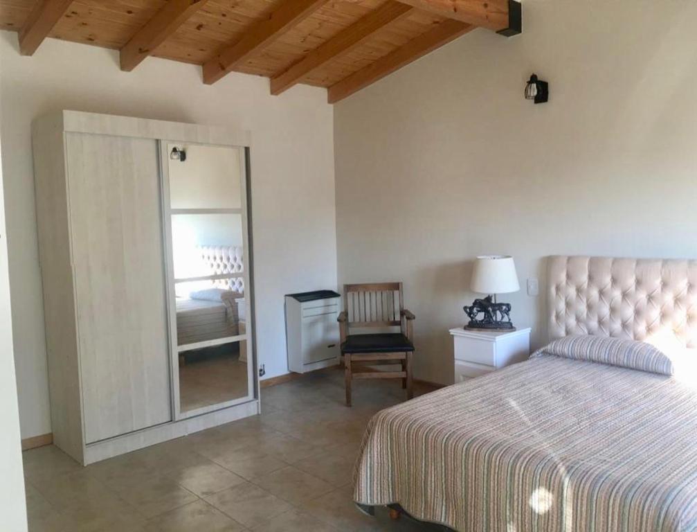 a bedroom with a bed and a mirror and a chair at La Calala Aparts in Esquel