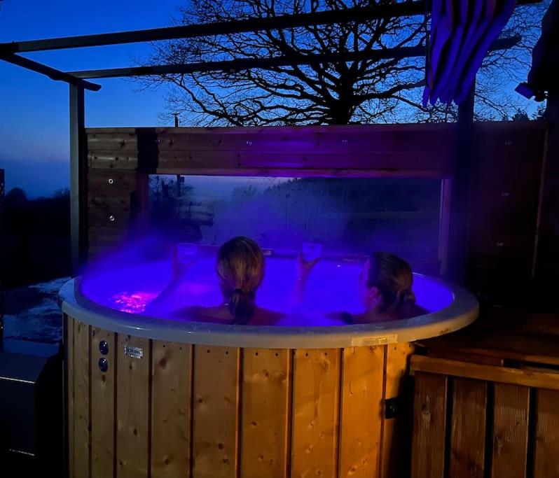 two people in a hot tub at night at Relaxing cottage bain nordique in Ancinnes