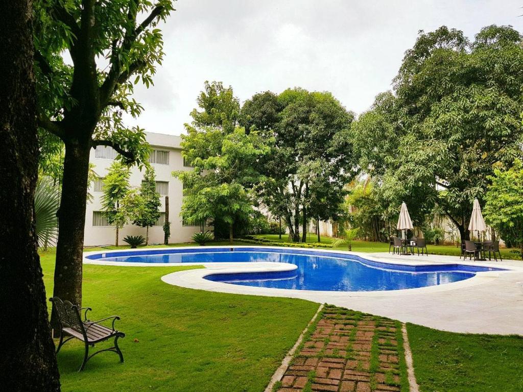 einen Pool in einem Garten mit einer Bank und Bäumen in der Unterkunft Hotel Verdi in San Juan Bautista Tuxtepec