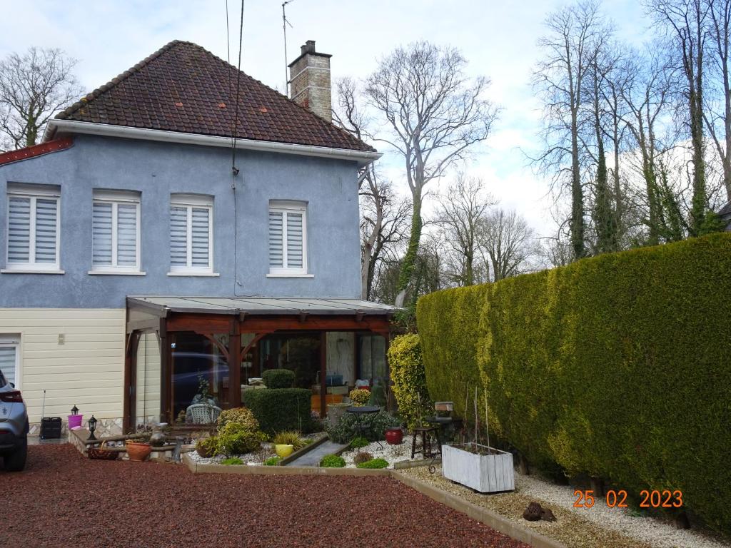uma casa azul com um alpendre e um quintal em Une nuit près de l eau em Hallines