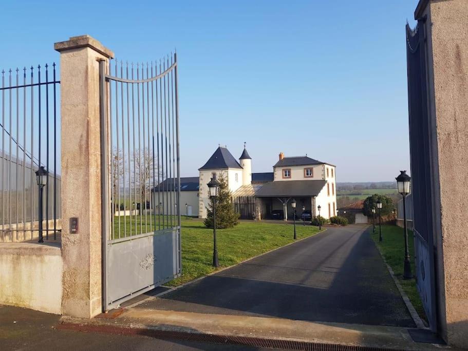 a gate to a driveway with a house behind it at Le Logis Cholet 49300 lieu exceptionnel en famille ou amis in Mazières-en-Mauges