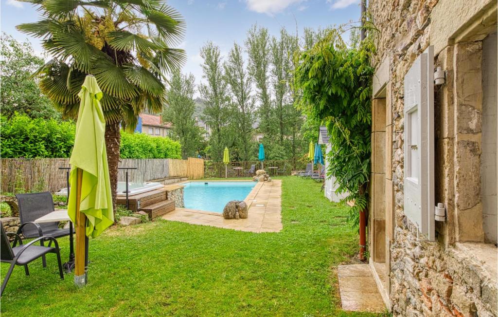 a backyard with a swimming pool and a palm tree at Cozy Apartment In Saint Jean Du Bruel With Private Swimming Pool, Can Be Inside Or Outside in Saint-Jean-du-Bruel