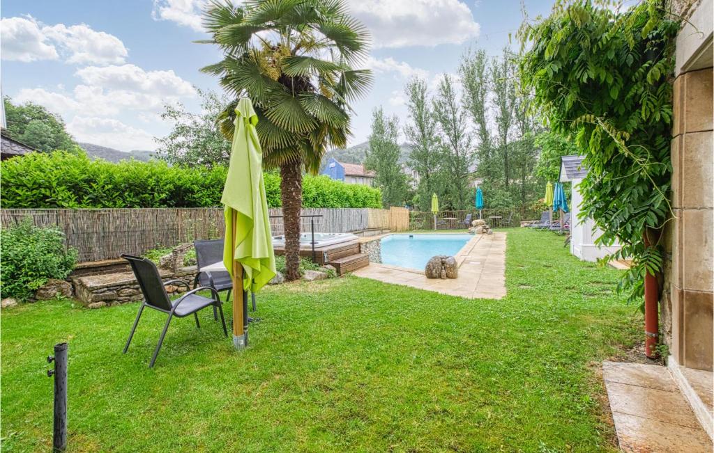 a yard with a pool and two chairs and an umbrella at Cozy Apartment In Saint Jean Du Bruel With Private Swimming Pool, Can Be Inside Or Outside in Saint-Jean-du-Bruel