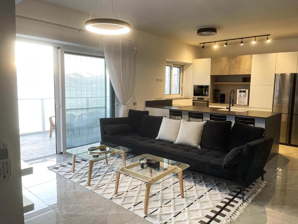 哈德拉的住宿－Sea Resort，一间带黑色沙发的客厅和一间厨房