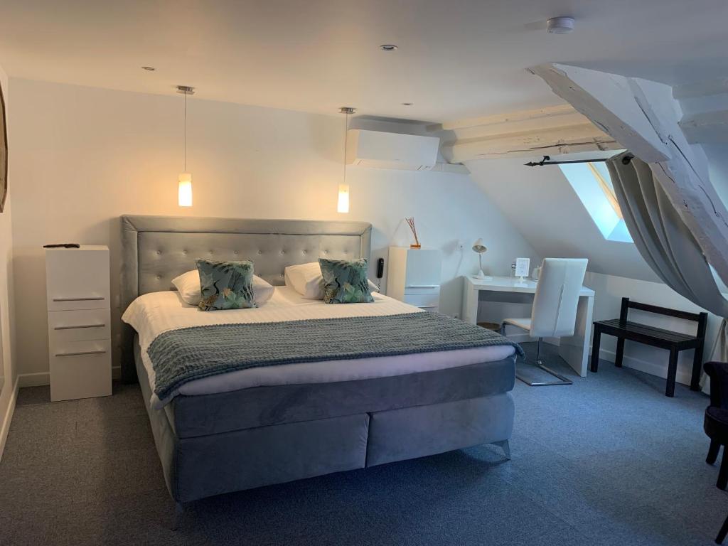 a bedroom with a bed and a desk and a chair at Hotel SPA Restaurant Au Cheval Blanc in Ribeauvillé