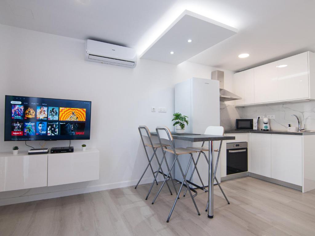 a kitchen with white cabinets and a table and chairs at BUNGALOW CAMPO DE GOLF in San Bartolomé de Tirajana