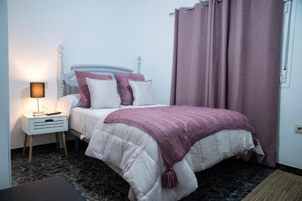 1 dormitorio con 1 cama con almohadas moradas y blancas en Apartamentos MC centro, en Ronda