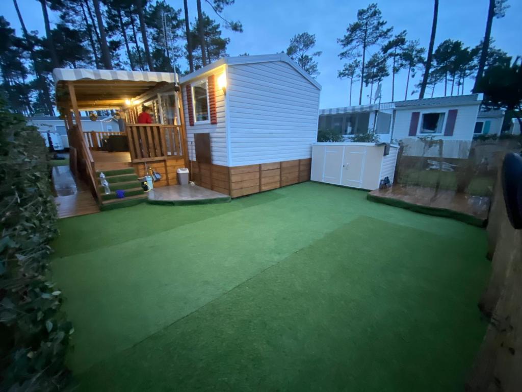 a backyard with a small shed with a green lawn at Coeur Des Sables in Saint-Julien-en-Born