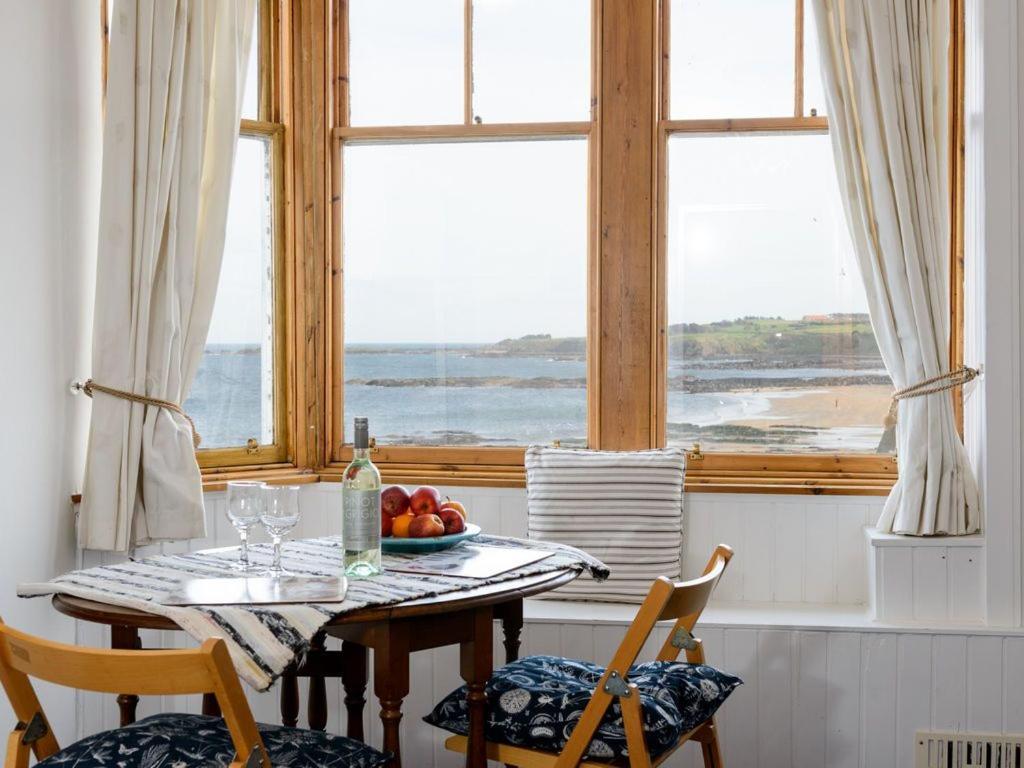 a table with a bowl of fruit in a room with a window at Bass Rock View in North Berwick