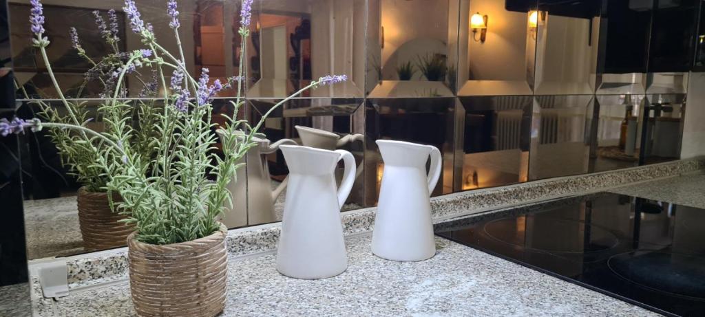 two white vases sitting on a counter with flowers at Fori's Nest Home SKG in Thessaloniki