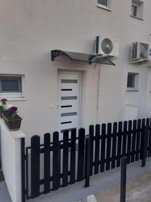 płot przed białym budynkiem z drzwiami w obiekcie Studio apartman LORENA w mieście Zadar
