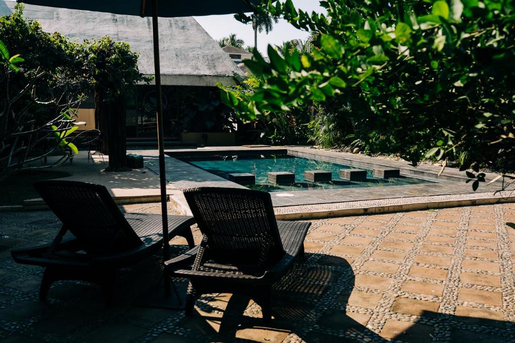 two chairs and an umbrella next to a swimming pool at Casa Sirena in Ixtapa
