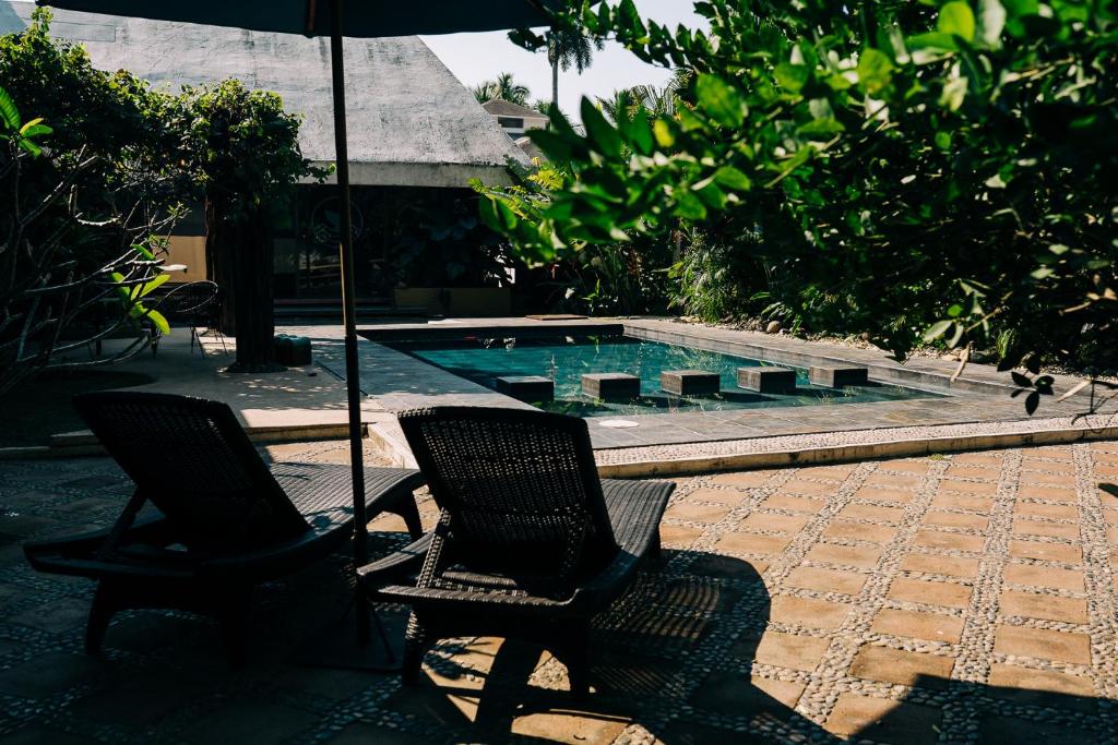 2 sillas y sombrilla junto a la piscina en Casa Sirena en Ixtapa