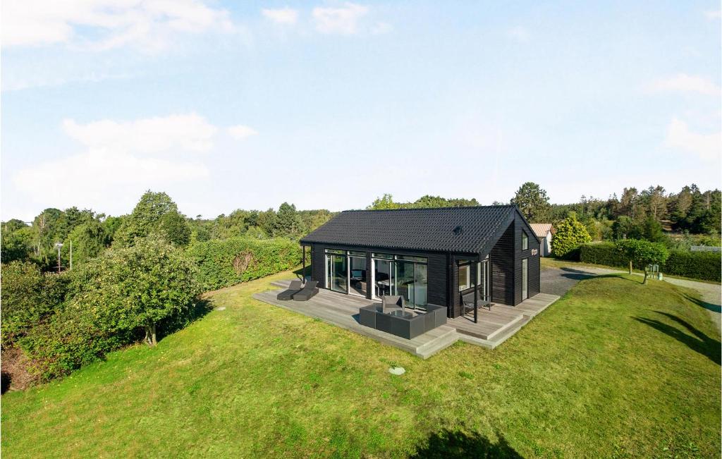 Ein schwarzes Haus auf einem Hügel mit einem grünen Feld in der Unterkunft 3 Bedroom Gorgeous Home In Ebeltoft in Ebeltoft
