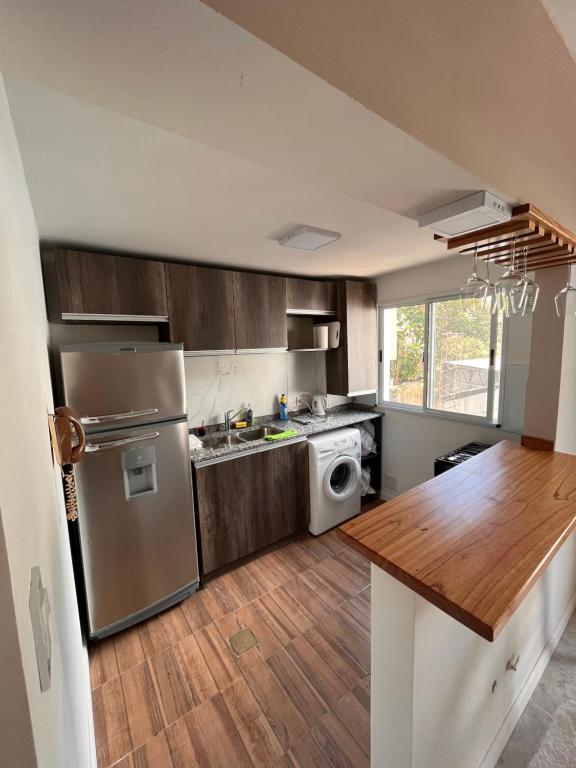 cocina con nevera de acero inoxidable y mesa de madera en DPTO MODERNO AMOBLADO TEMPORARIO PARANÁ, Entre Ríos en Paraná