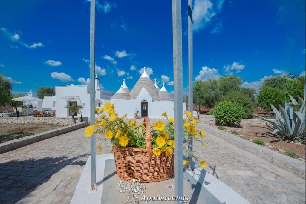 a basket of yellow flowers on a pole in front of a church at Beautiful Trullo Paleo in Ceglie Messapica in Ceglie Messapica