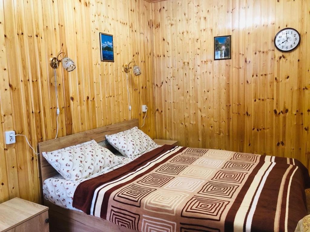 ガグラにあるДом под ключ Арабикаの木製の壁のベッドルーム1室(ベッド1台、時計付)