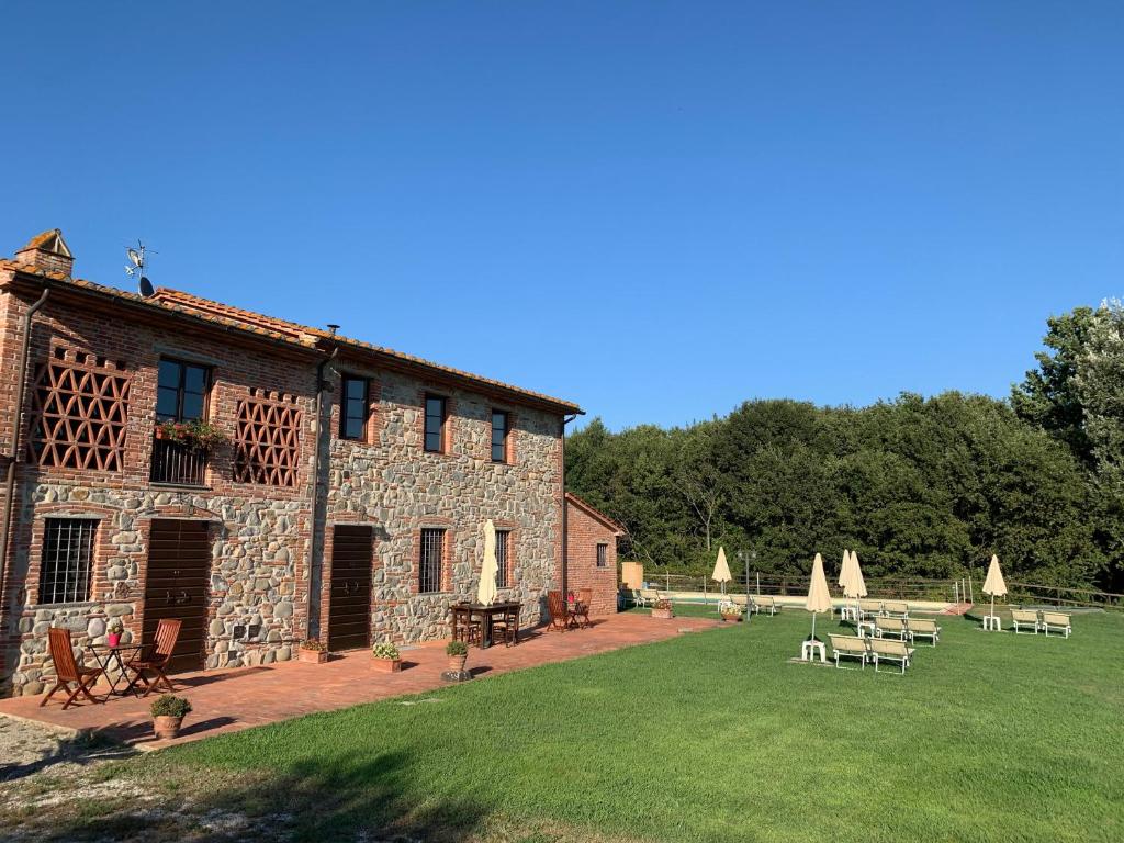 un edificio in pietra con tavoli e ombrelloni in un cortile di Sibolla Holidays ad Altopascio