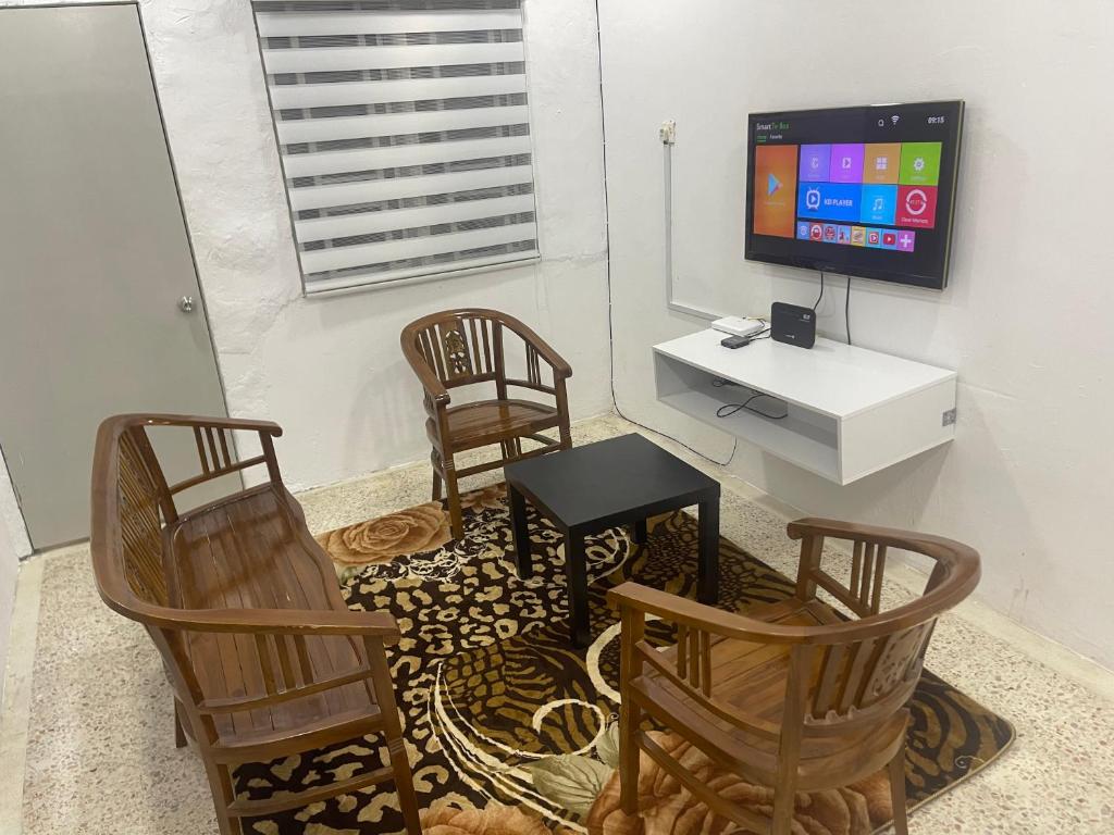 - un salon avec 2 chaises, une table et une télévision dans l'établissement D Alfa homestay, à Port Dickson
