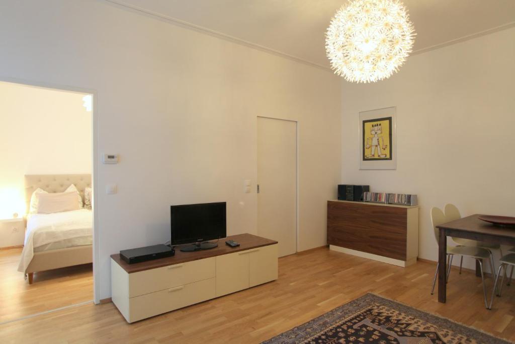 uma sala de estar com uma televisão, uma cama e uma mesa em Casa Nostra - Moderne Stadtwohnung mit Balkon em Viena