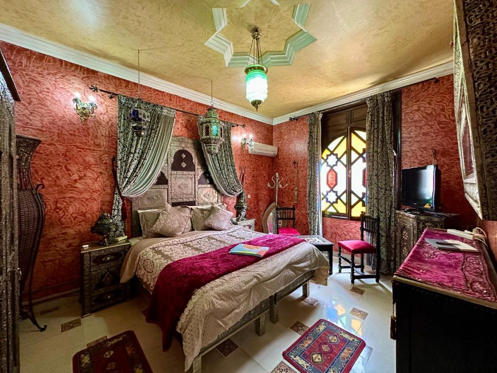 um quarto com uma cama num quarto com paredes vermelhas em Riad Mogador em Meknès