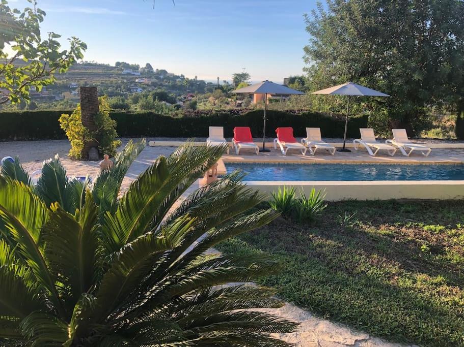 a swimming pool with lounge chairs and umbrellas next to at Lovely Appartment 'Solana' with big garden, nice pool in Teulada