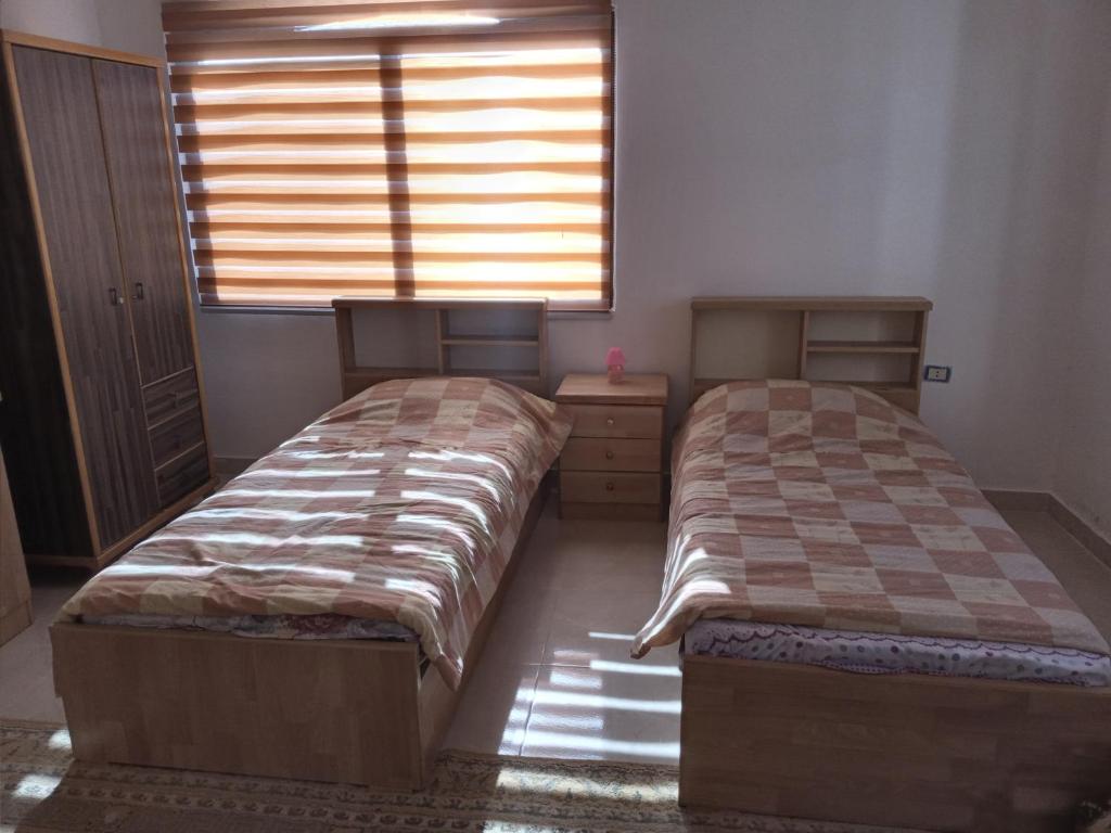 two beds sitting in a room with a window at شقة فندقيه مفروشه in Jerash