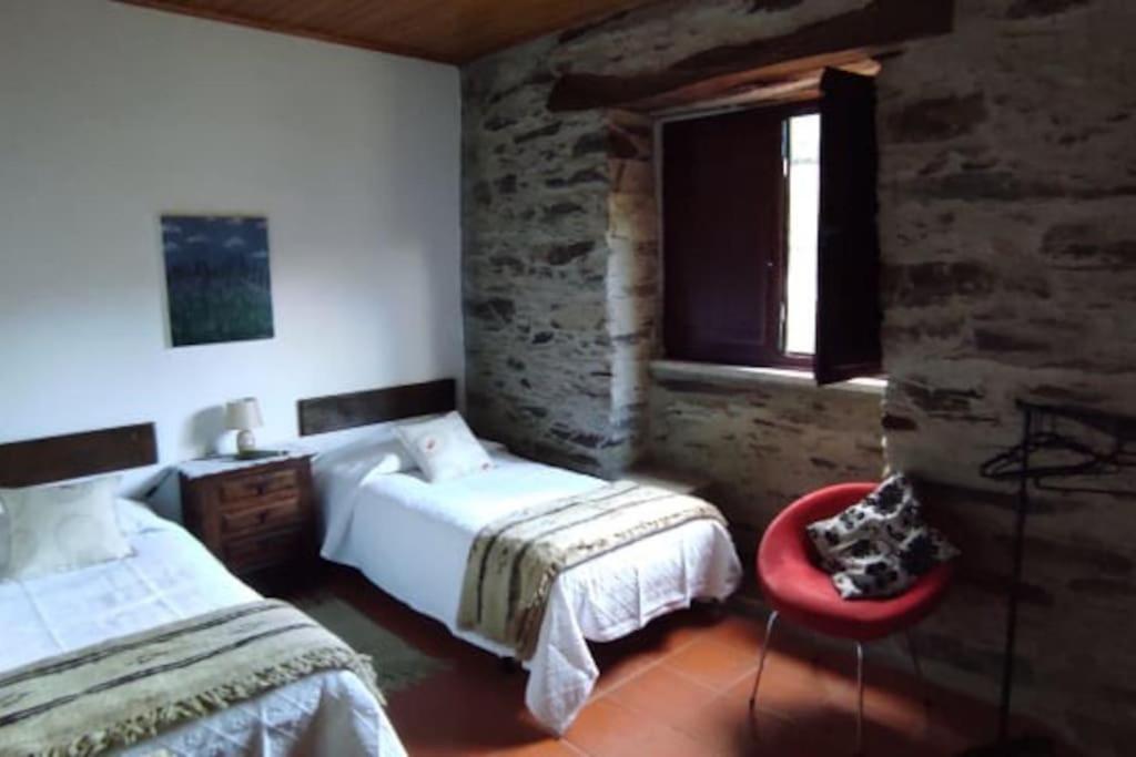 - une chambre avec deux lits et une chaise rouge dans l'établissement Casa de Campo - Casa da Ribeira, 