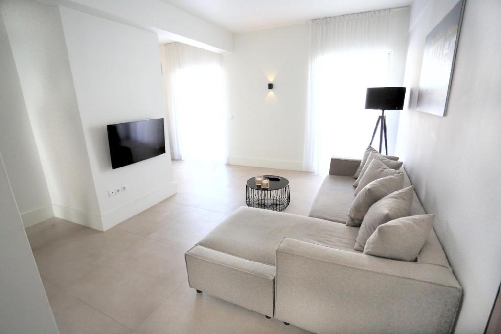 Sala de estar blanca con sofá y TV en Junior Unicorn Suite, en Atenas