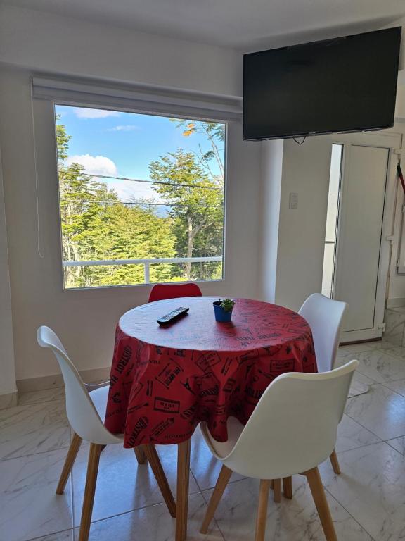 mesa de comedor con mantel rojo y sillas blancas en ALAKALUFES House en Ushuaia