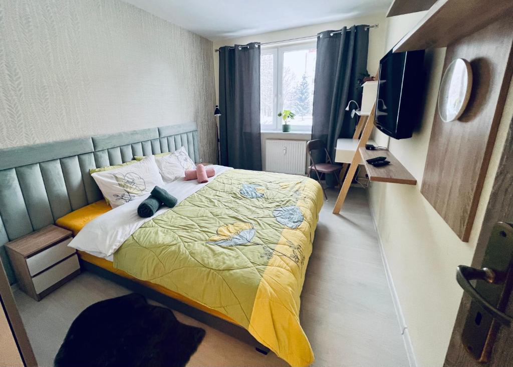a bedroom with a bed with a yellow comforter at Kolobrzeska PRL Apartment with modern touch in Białogard